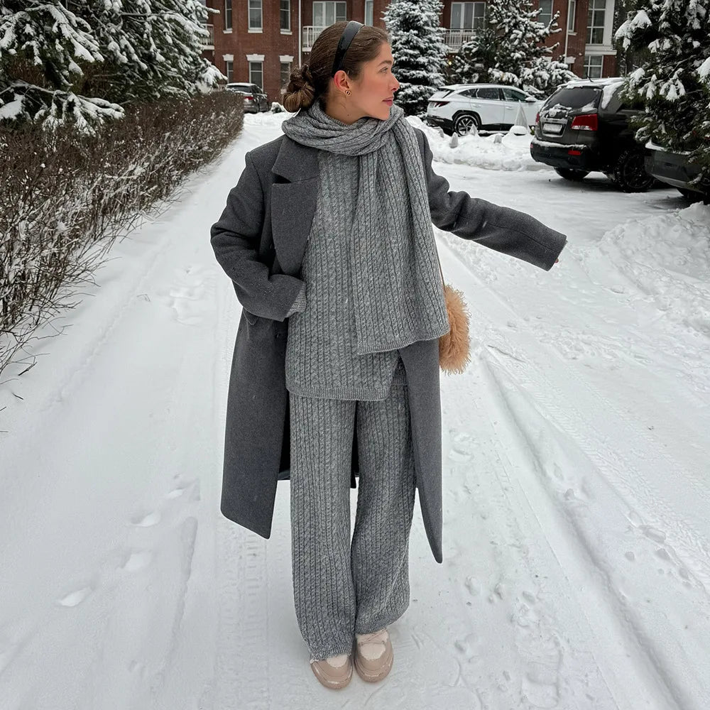 Woman in a gray outfit walking on a snow-covered street