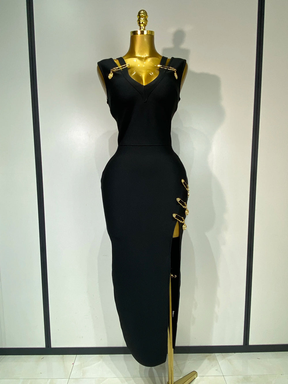 Black dress with gold accents on a mannequin against a white background