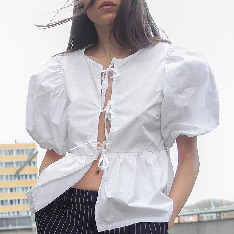 Person wearing a white blouse with puffed sleeves against an urban background