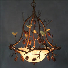 Decorative chandelier with branches, birds, and pinecones against a dark background