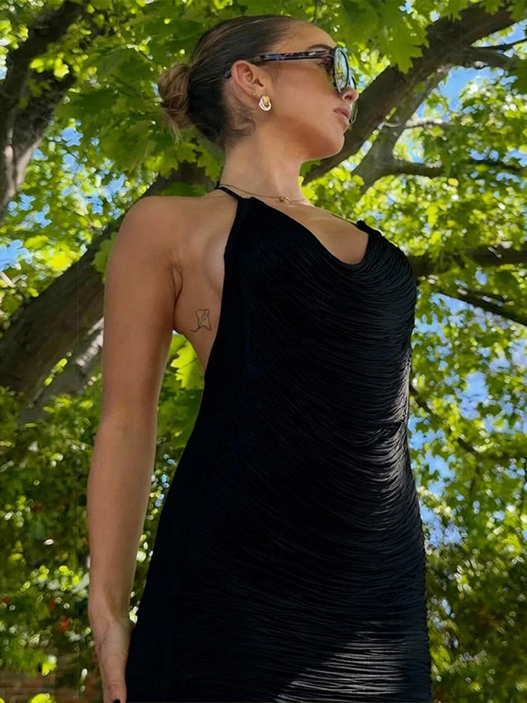 Woman in a black dress standing outdoors with trees in the background