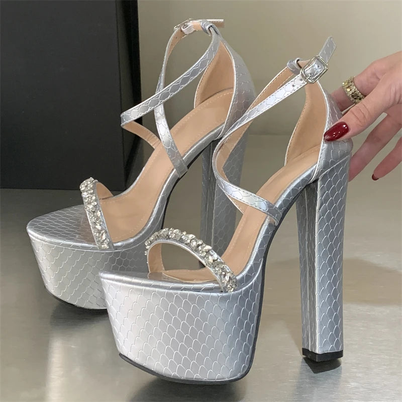 Silver high-heeled platform shoes with strappy design on a neutral background