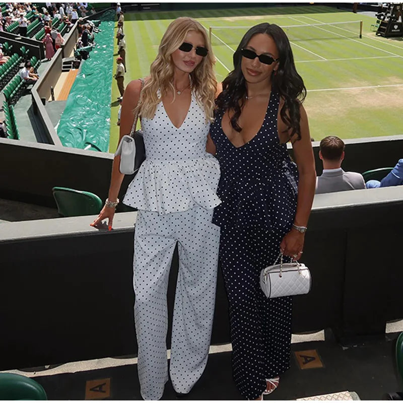 Two women in polka dot outfits standing on a tennis court