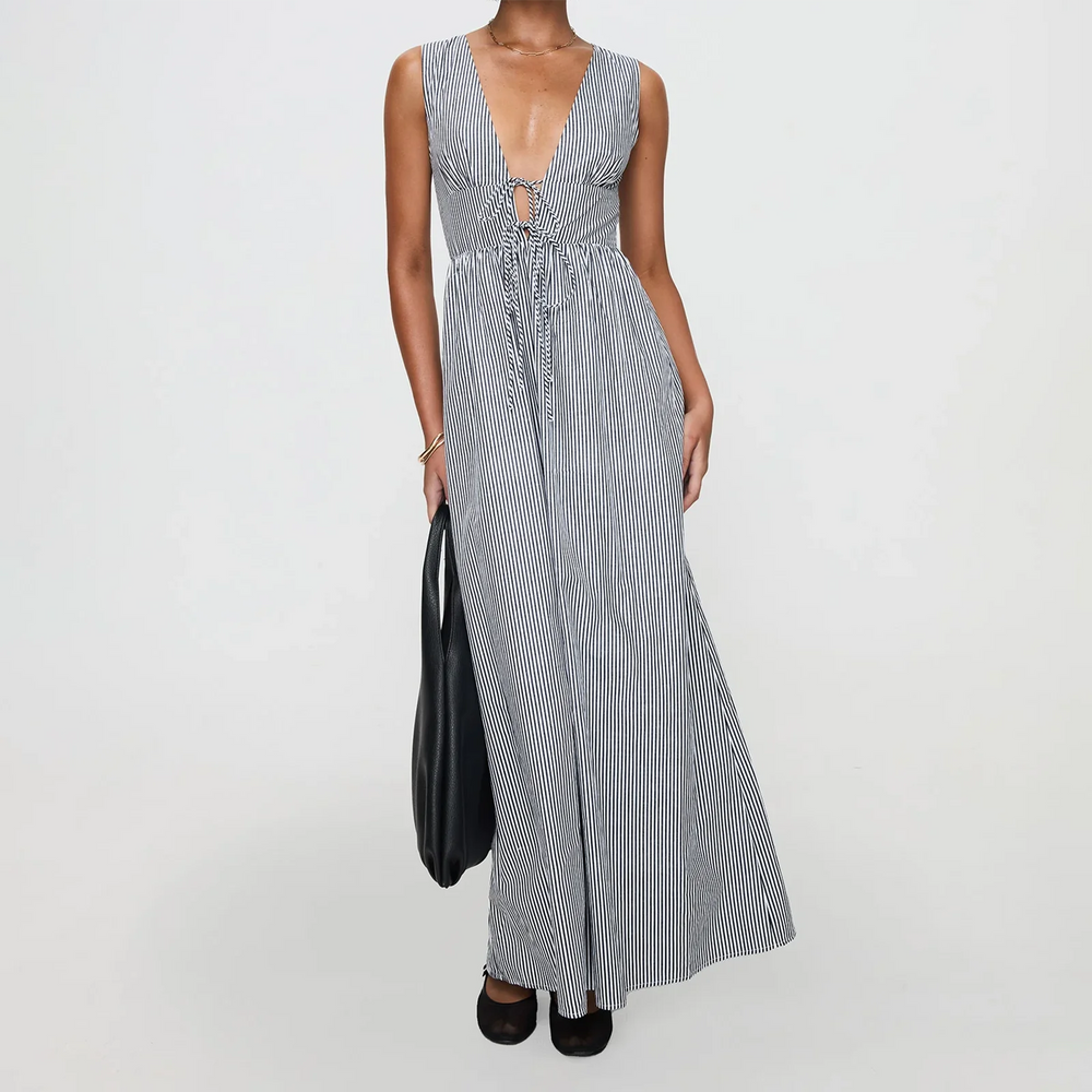 Woman wearing a long striped dress holding a black bag on a white background