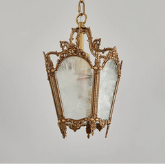 Decorative hanging lantern with ornate gold frame and glass panels on a gray background