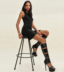 Black patent leather knee-high gladiator boots with cutout straps and stiletto heel
