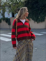 Woman wearing a red and brown striped sweater and plaid skirt on a street.