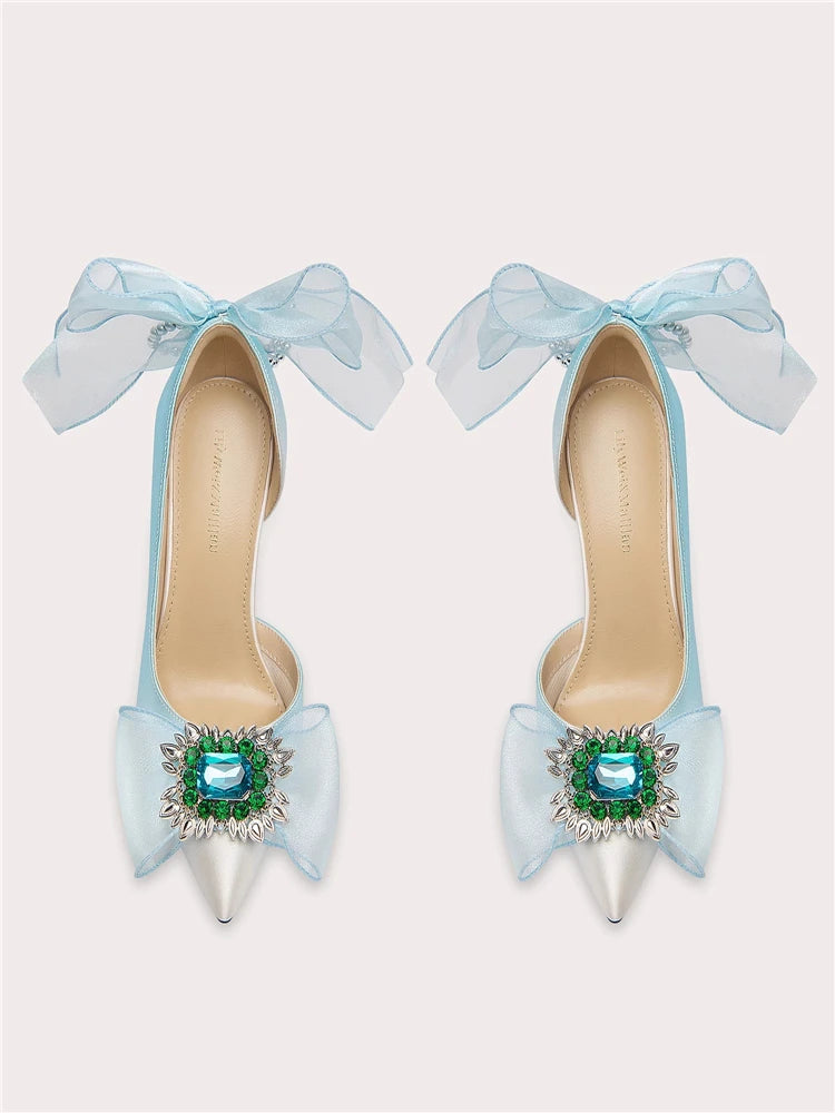 Light blue high-heeled shoes with large bows and decorative elements on a white background
