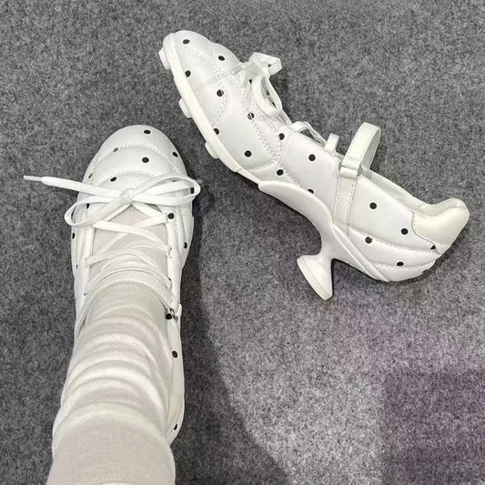 White polka dot Mary Jane heels and a pair of black ones on a grey carpet.