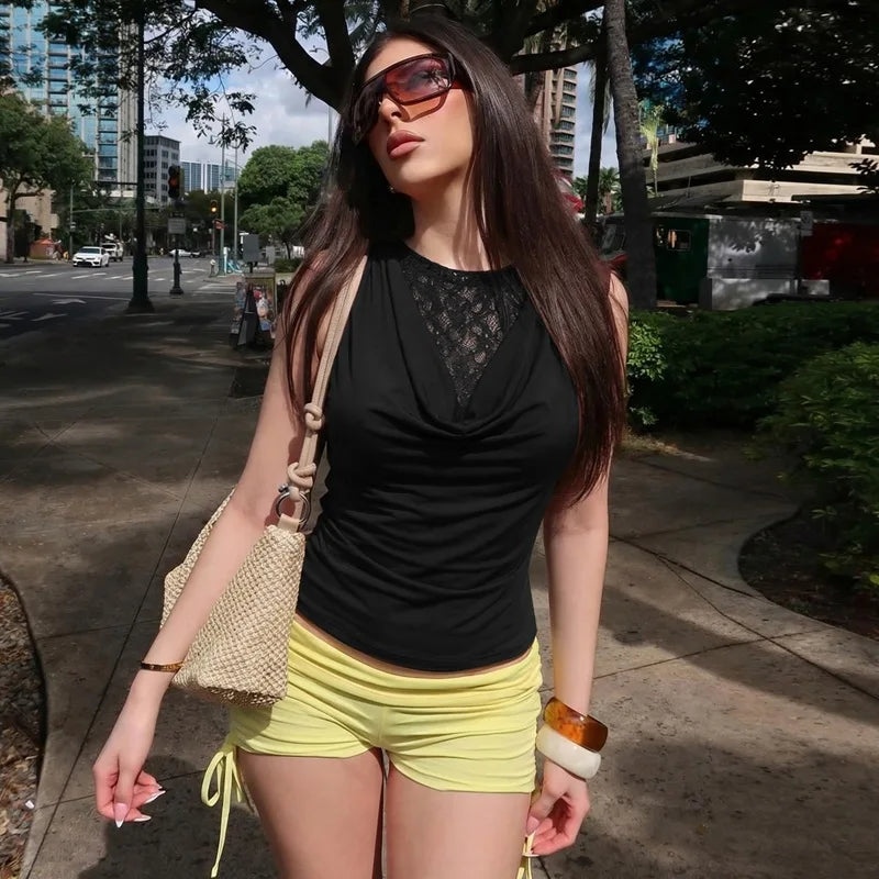 Woman in black top and yellow shorts walking on a city street.