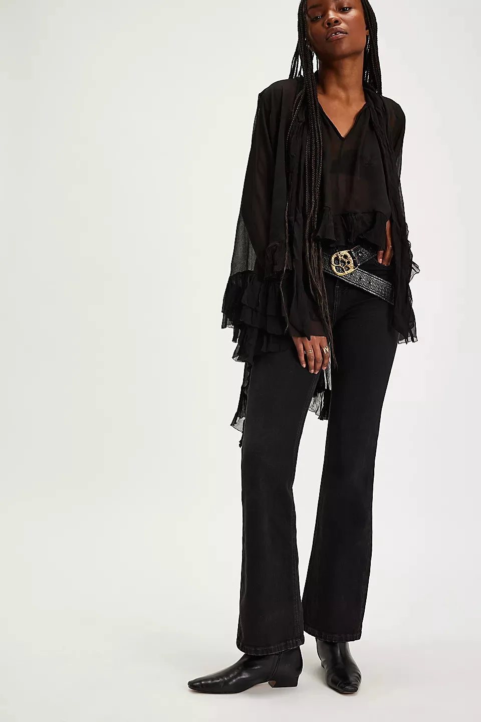 Person wearing a black outfit with a belt and boots on a white background