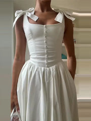White dress with bow straps worn by a person indoors.