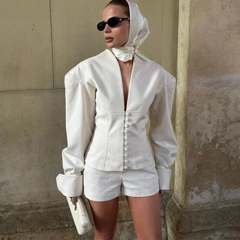 Person wearing a white outfit with a hood against a beige wall.