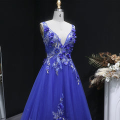 Blue evening gown with floral embellishments on a mannequin against a dark background.