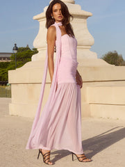 Woman in a pink dress standing in front of a classical architectural structure.