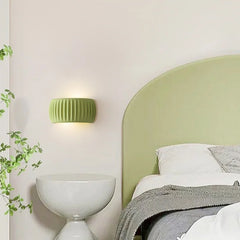 A French cream pumpkin wall lamp casting a soft glow in a cozy bedroom with a rustic wood headboard. A