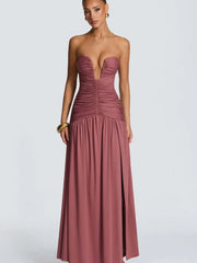 Woman wearing a strapless, long, mauve dress on a white background