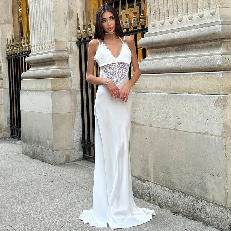 Woman in a white evening gown standing against a stone building.