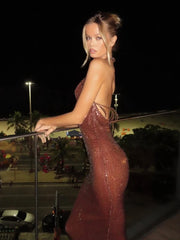 Woman in a sparkly red dress standing on a balcony at night.