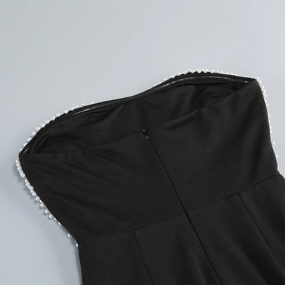 Black dress with pearl detailing on a gray background