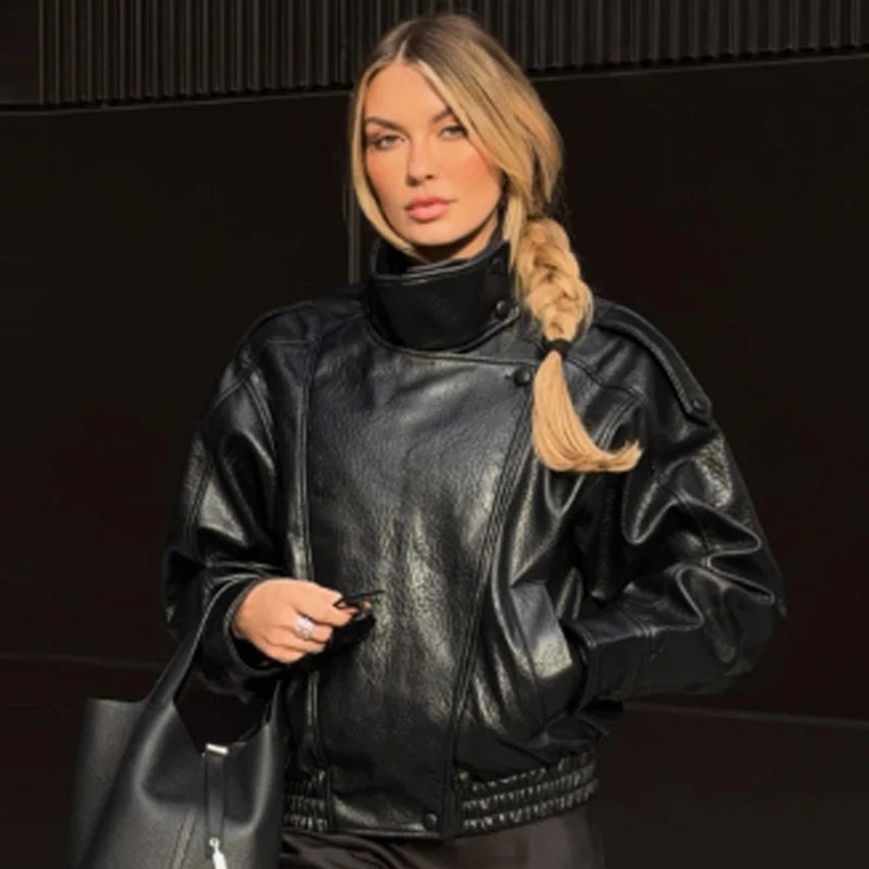 Blonde woman in a black faux leather jacket with a high collar.