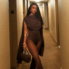 Woman in a hallway wearing a dark outfit with a long coat.
