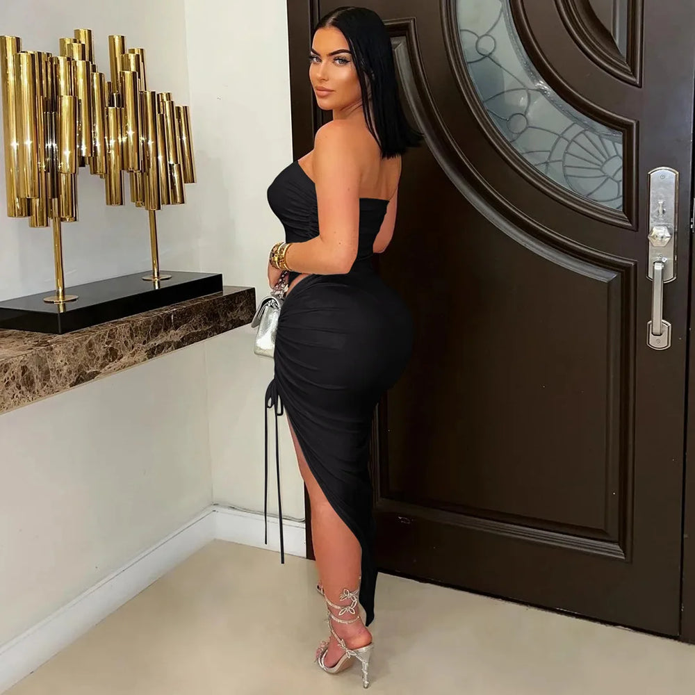 Side angle of a woman in a black ice-silk fabric texture on a co-ord party set,  in a stylish interior setting with a decorative lamp and door.