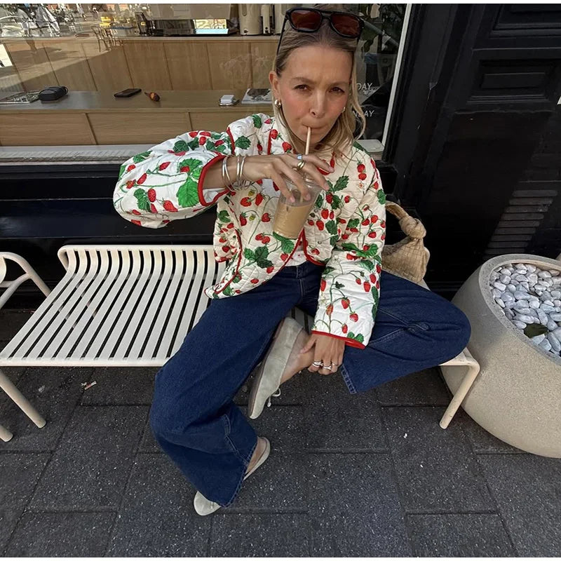 Woman in a colorful jacket sitting on a bench outdoors