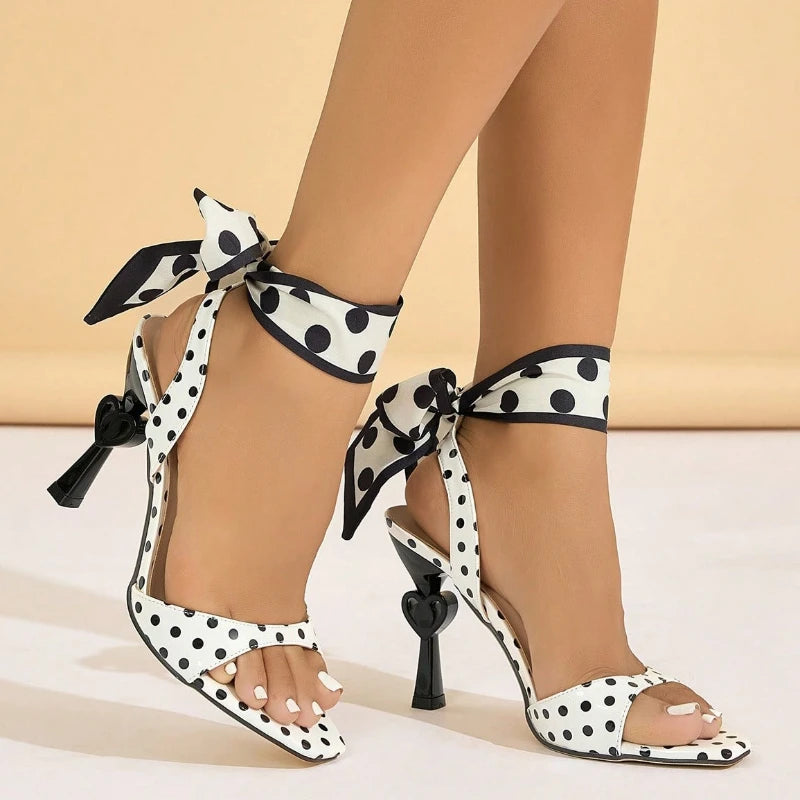 Polka dot high-heeled shoes with ribbon ties on a neutral background
