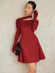 Woman wearing a red off-shoulder dress against a textured beige wall