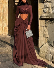 Woman in a burgundy evening gown standing in front of a stone building.