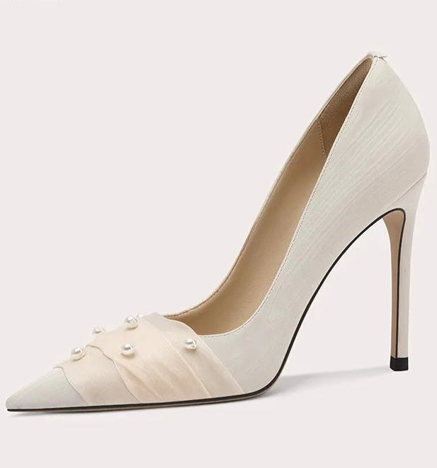 White high-heeled shoe with pearl details on a light gray background