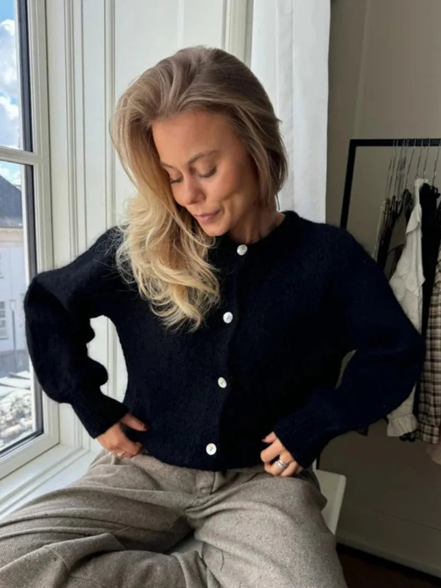 Woman wearing a dark blue cardigan sitting by a window