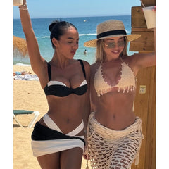 Person wearing a black and white contrast trim bikini top and bottoms with a wrap skirt, lounging on a beach chair.