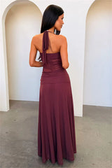Woman wearing a long brown dress with a single shoulder strap in an indoor setting.