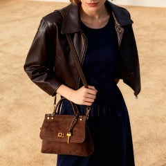 Person wearing a brown leather jacket and holding a matching brown handbag against a beige background
