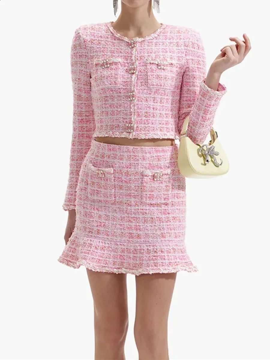 Woman wearing a pink tweed outfit with a matching handbag on a white background