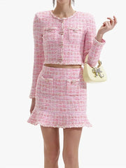 Woman wearing a pink tweed outfit with a matching handbag on a white background