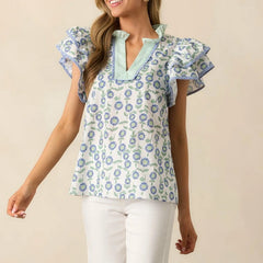 Woman wearing a floral blouse with ruffled sleeves against a beige background