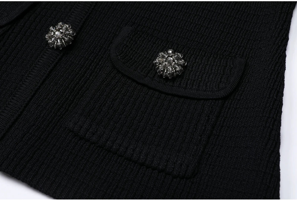 Close-up of the textured knit fabric and pocket detail with jeweled button on the black cardigan.