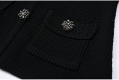 Close-up of the textured knit fabric and pocket detail with jeweled button on the black cardigan.