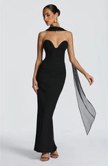 Woman wearing a black strapless gown with a sheer overlay on a white background