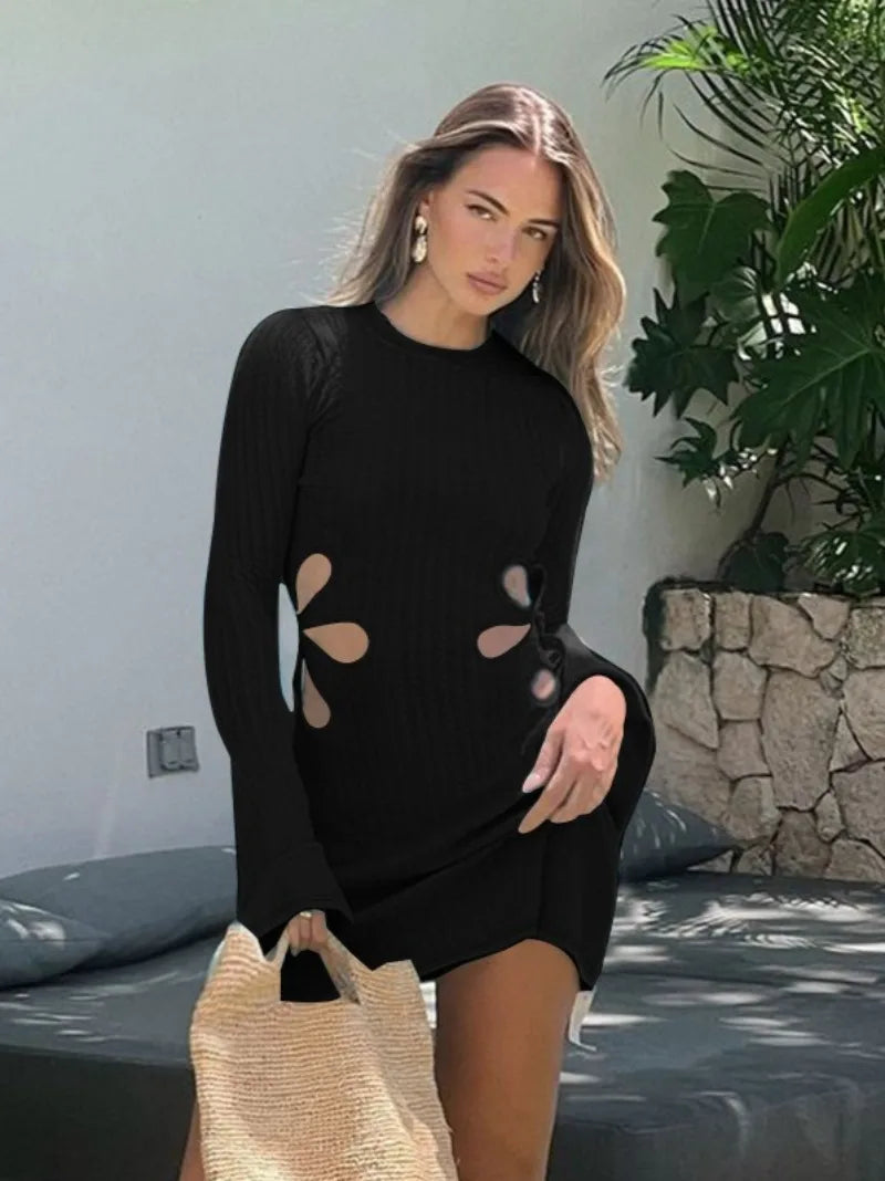 Woman wearing a black dress with floral cutouts in an outdoor setting.