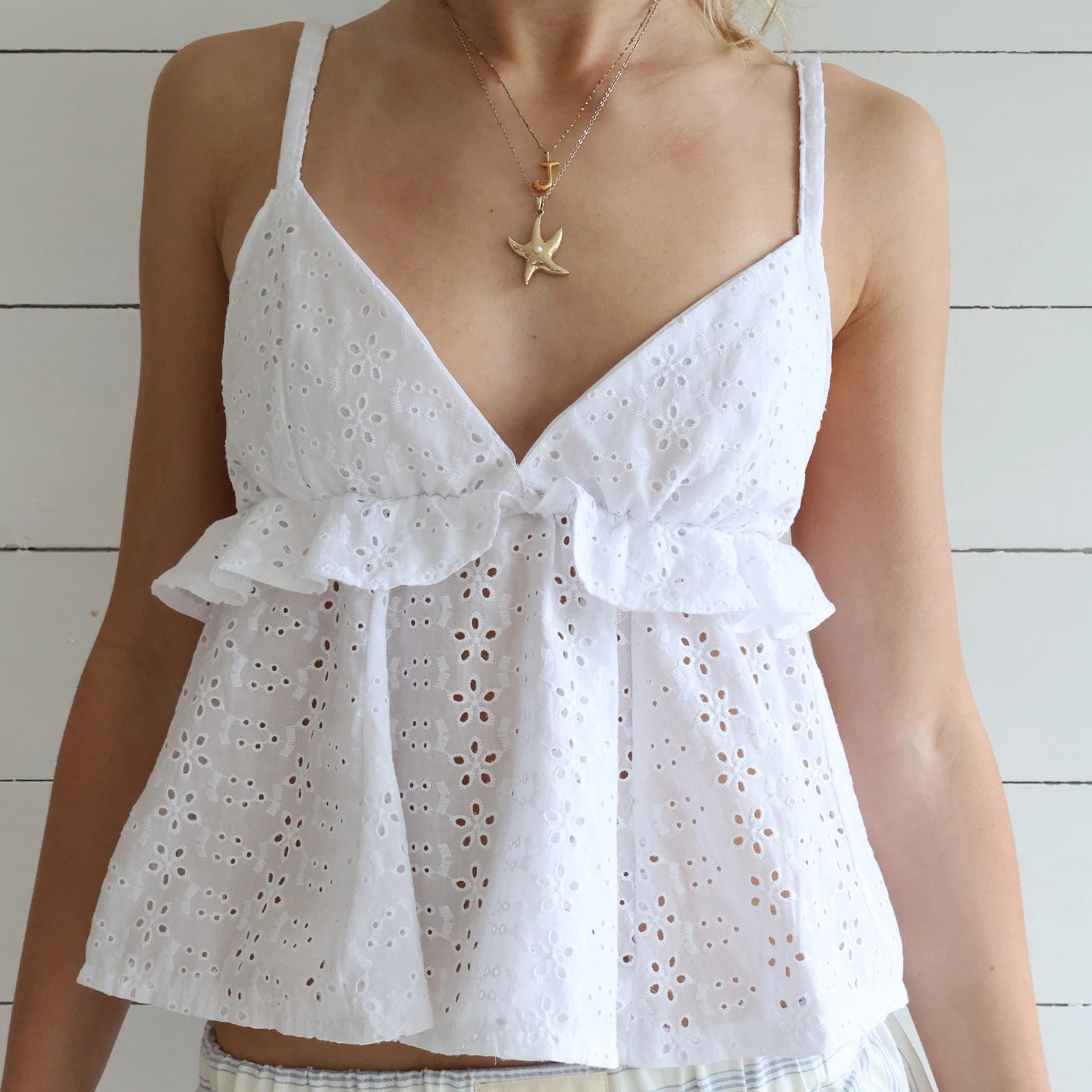 White eyelet top worn by a person with a wooden background