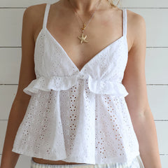 White eyelet top worn by a person with a wooden background