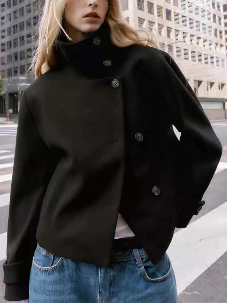 Model wearing a black high neck cropped jacket with blue jeans.