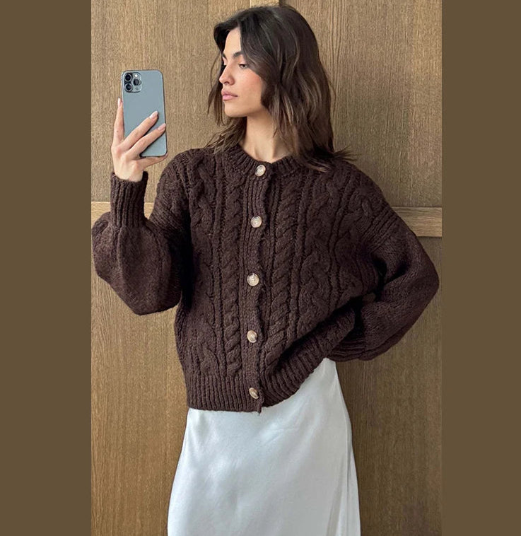 Woman wearing a brown cable knit cardigan taking a mirror selfie.