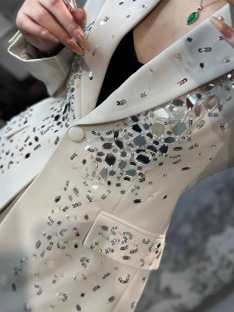 Close-up of a white coat with decorative mirror片片, worn by a person.