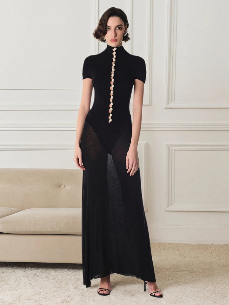 Woman wearing a black outfit with sheer panels in an elegant room.
