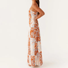 Woman wearing a floral dress with orange and white pattern on a plain background